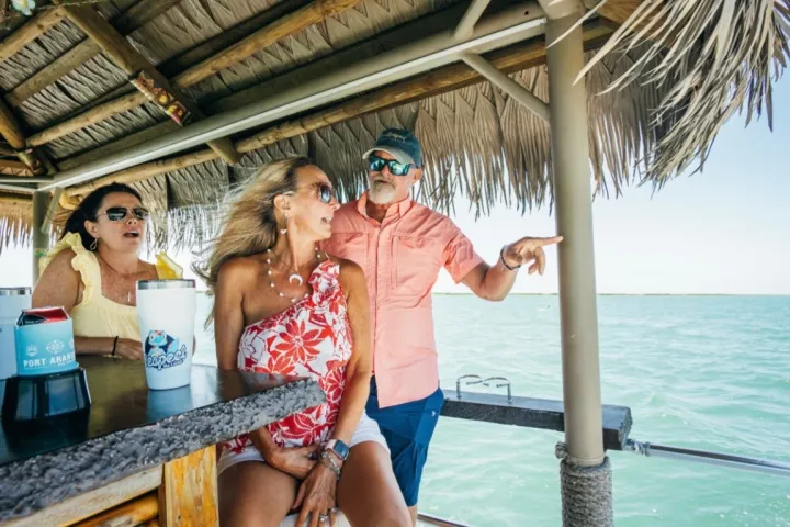 People enjoying a drink at a tiki bar on the water.