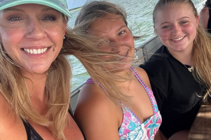 Three people smiling on a boat with water in the background.