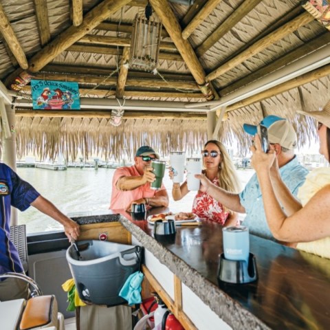 Group of people enjoying drinks at a tiki bar on a boat.
