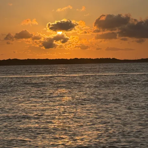 Sunset over a calm sea with clouds and an illuminated sky.