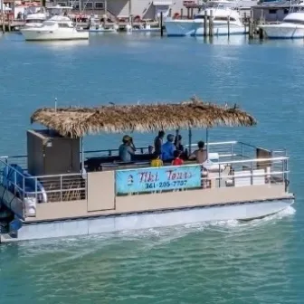 Tour boat with thatched roof sailing on a marina with several people onboard.
